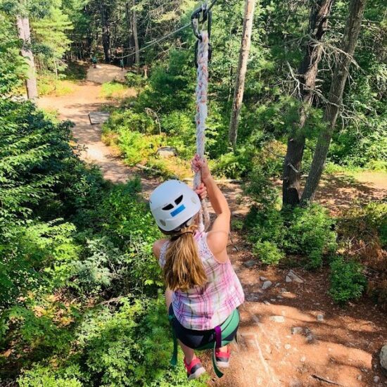 Child swinging on rope wearing safety helmet at YMCA Ocean Community